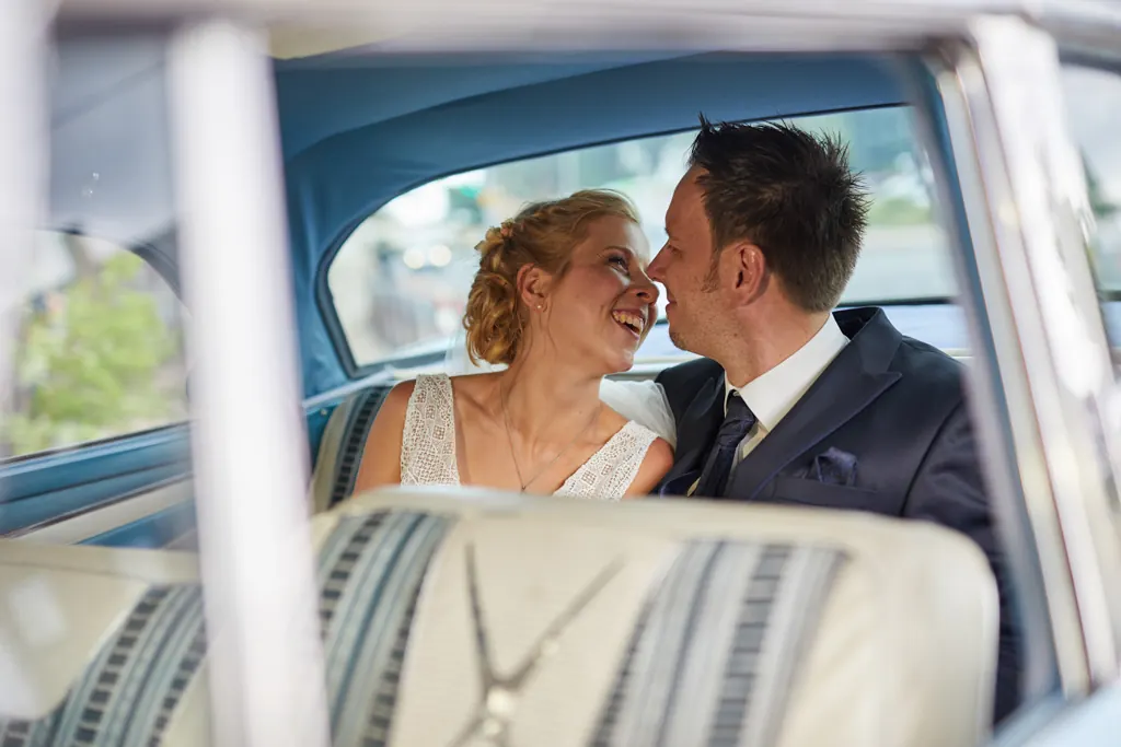 Lachendes Brautpaar in einem Oldtimer